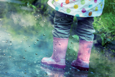 cute little girl is playing in muddy puddles