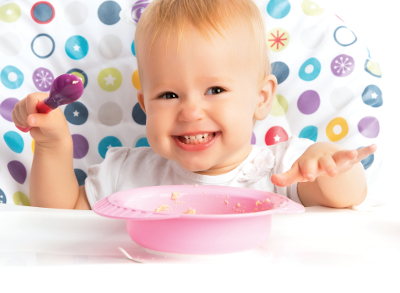 cheerful happy baby child eats itself with a spoon