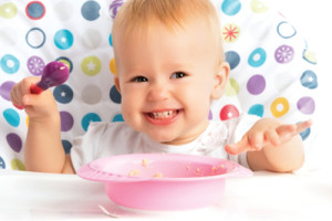 cheerful happy baby child eats itself with a spoon